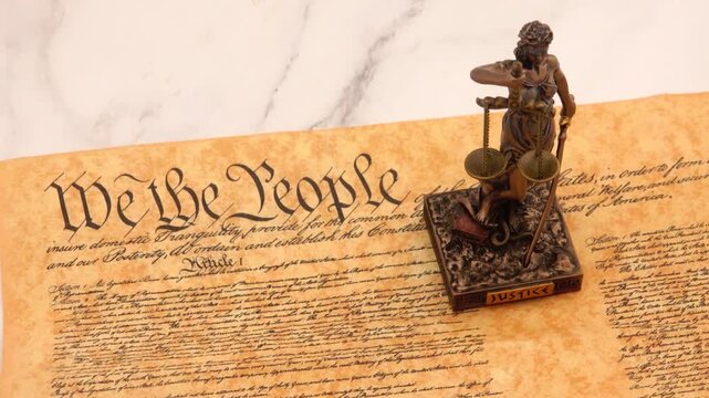 A powerful symbol of law and democracy, the Statue of Justice stands prominently before the United States Constitution, representing fairness, balance, and the rule of law.