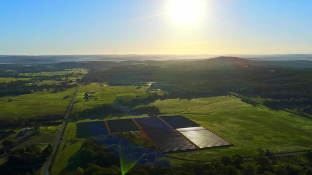 Expansive solar energy site covering open field with panels producing renewable power, panoramic contextual overview, golden hour