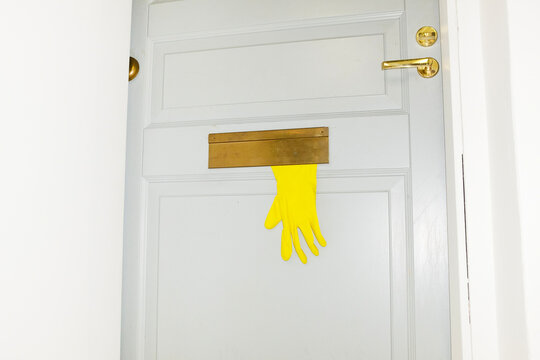 Conceptual photo of yellow plastic gloves peeking from mail box 