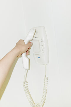 Hand holding old landline phone with wire with hard direct flashlight