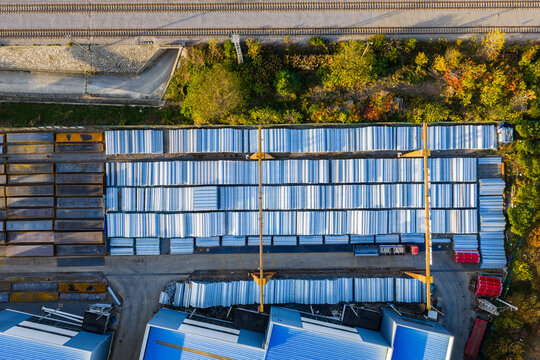 Top-Down View of Stacked Steel Beams in Industrial Yard


