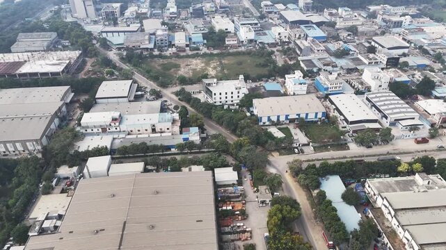 Drone footage over Greater Noida&rsquo;s industrial zone, showcasing factory sheds, mixed land use, and wide roads, softened by smoggy skies that reflect ongoing air pollution in the expanding city.
