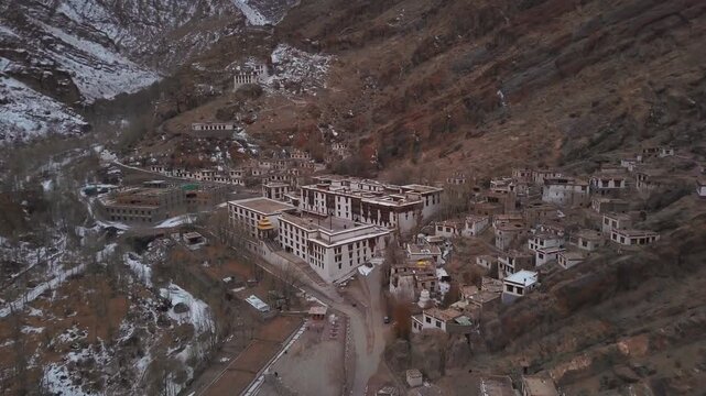 Rare aerial view of completely empty Hemis Monastery complex nestled in snowy Himalayan valley on cold winter morning in Ladakh, with whitewashed buildings dotting rugged brown slopes.