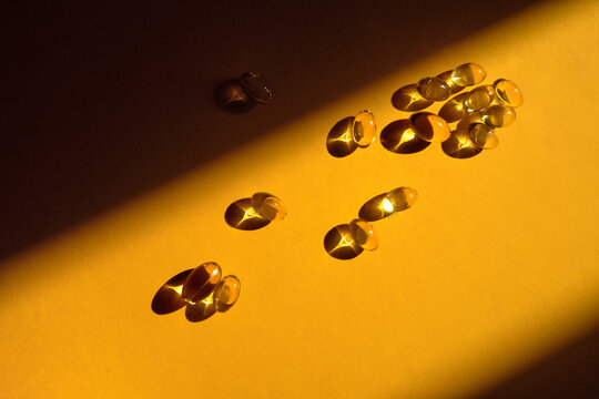 Golden Omega 3 Capsules on Bright Orange Backdrop with Copy Space.