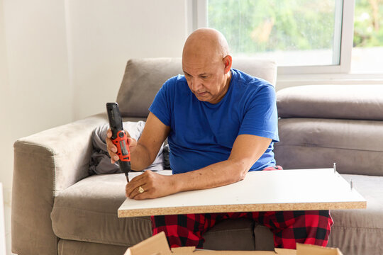 Man Assembling Furniture in Living Room During Afternoon Hours