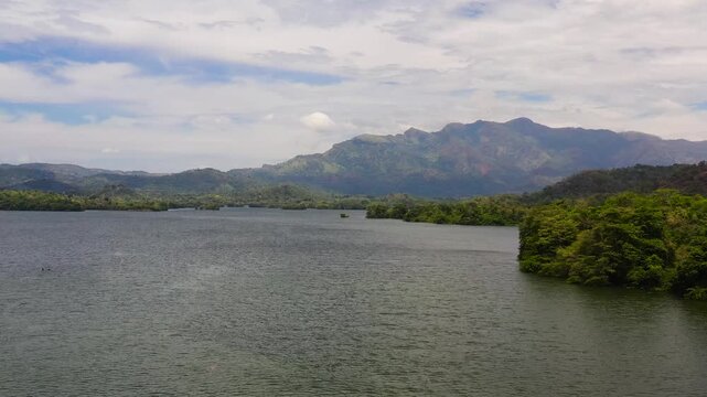 Top view of lake with islands surrounded by mountains with a tropical forest. Loggal Oya Reservoir. Sri Lanka.