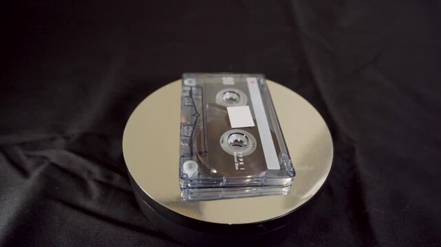 Vintage audio cassette tape spinning on a reflective turntable.