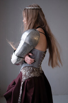Woman in armor stands in studio setting
