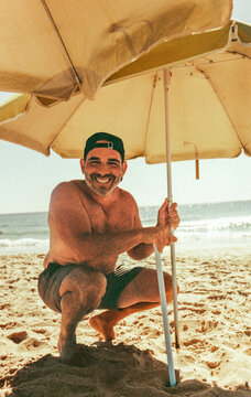 Smiling Man Setting Up Beach Umbrella