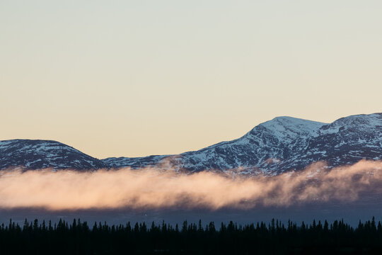 low clouds drifting over snow covered mountains