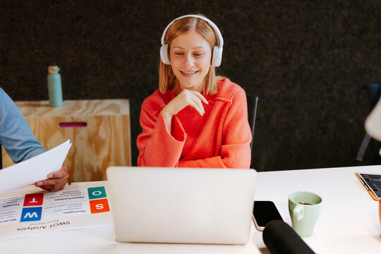 Worker using laptop and headphones in office setting