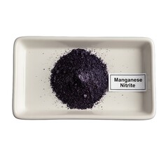 A pile of dark purple manganese nitrite powder on a white rectangular ceramic plate with a label from a top-down viewpoint in a laboratory environment