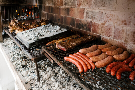 Assorted meats and sausages grilling over hot coals