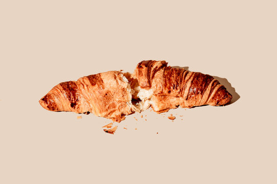 a delicious croissant, split in half, on a beige background