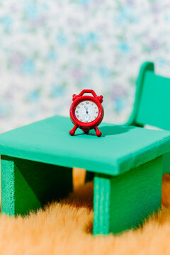 a miniature red alarm clock on a green table