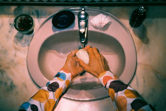 a man washes his hands at a bathroom sink, 35mm film