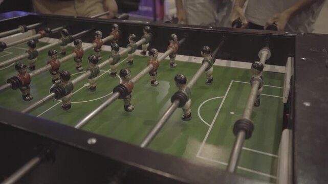 Close-up of a foosball table pitch with players in action positions.