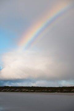 Rainbow arching over cloudy coastal sky