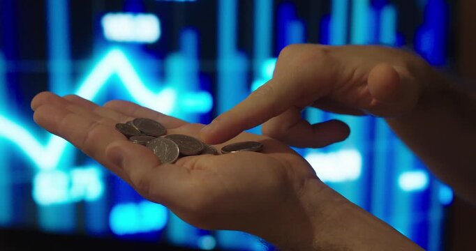 Conceptual stock footage showing hands holding a few coins in front of a digital trading chart, symbolizing small gains, cautious trading, modest profits, and realistic investment outcomes.