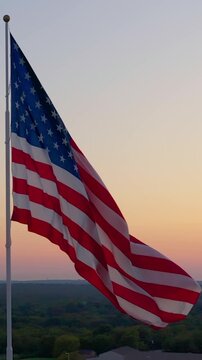 Vertical Aerial Close-up: US Flag Waving at Sunset with Drone Orbit
