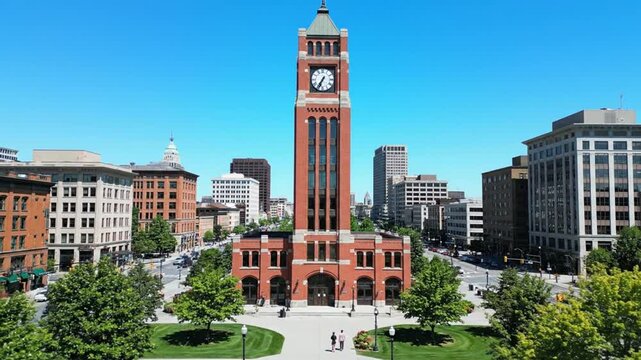 A large red brick clock tower in a city.