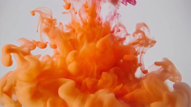 Vibrant orange ink splash explosion in water on gray background for creative designs