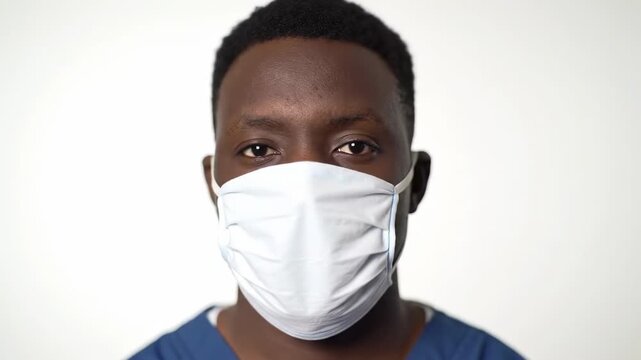 A man wearing a face mask looks directly at the camera
