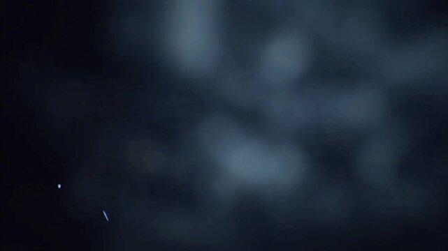 A dark, atmospheric background with faint wisps of smoke or mist.