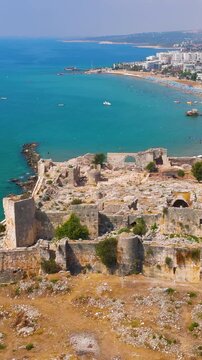 Vertical video. Vertical video. Kizkalesi, Mersin, Turkey. Aerial coastline view with sandy beaches, Maiden Castle on island and historic Korykos Castle on shore, summer. Aerial View. Rich colors. Ri