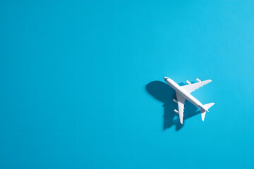 A top view of a small white toy airplane on a blue background. Summer vacation and travel concept.