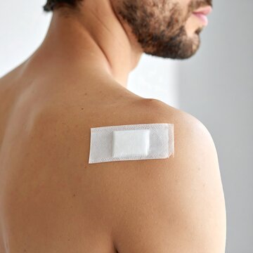 Close-up of a man's bare back with a rectangular bandage