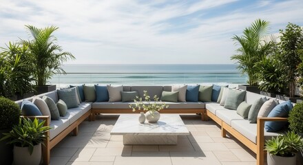 Fototapeta premium Outdoor patio with U-shaped modular sofa marble coffee table potted plants and an expansive ocean view under a clear sky