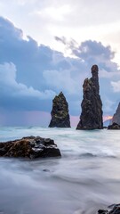 Dramatic sea stacks rise from the ocean under a cloudy sky