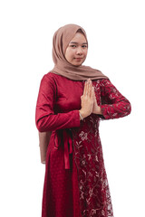 Young woman in maroon dress and hijab making respectful greeting gesture with friendly expression