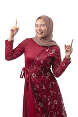 Young woman in elegant red dress and hijab pointing upwards with cheerful expression