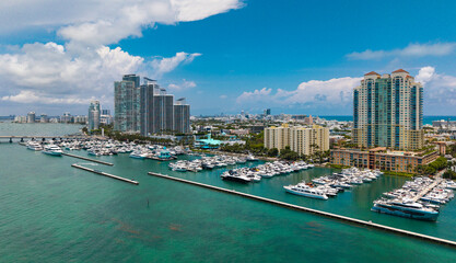 Fototapeta premium Luxury yacht docked at Miami marina. Aerial view of coastline in Miami. Sailboat cruising along the Miamis shore. Miami skyline above harbor.
