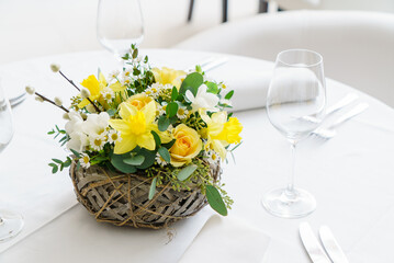 Fototapeta premium Bright yellow flowers and soft white blooms create a festive atmosphere for Easter dining
