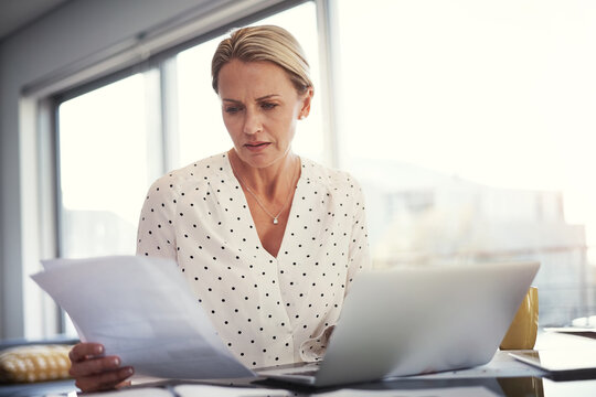 Laptop, woman or worry with documents in home for invoice review, compare client data or remote work. Freelance accountant, mature person and tech with concern for receipts and cash flow verification