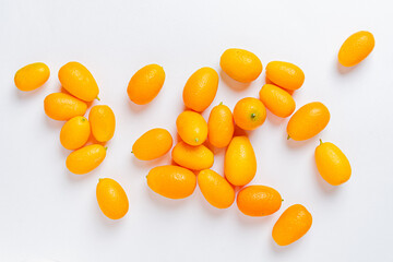 Fresh kumquats gleam in soft light, showcasing their vibrant orange hue and smooth skin