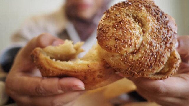 Hands hold a fresh bread roll in a cafe