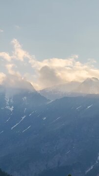 4K Vertical shot of clouds surrounding the snowy Himalayan mountain peaks during the sunset as seen from Killar in Chamba district, Himachal Pradesh, India. Scenic view of snowy Himalayas.