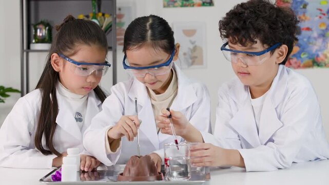Asian Students in Lab Coats Conduct Baking Soda and Vinegar Volcano Experiment