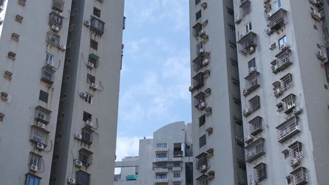 High-rise residential apartment buildings in Xiamen, China, featuring dense rows of windows, external air conditioning units. High-density urban housing, populated and crowded living conditions.