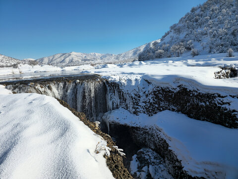 A winter waterfall drops into a snowy gorge, surrounded by frozen terrain and distant mountains under a clear blue sky.
📍Marivan, Kurdistan 