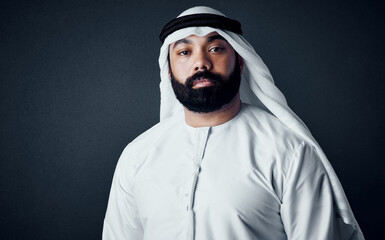 Obraz premium Muslim, portrait and business man in studio, serious and ambition as finance advisor. Professional, islam and traditional person, confidence and investment consultant on dark background in UAE