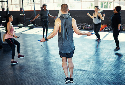 Fitness, circle or people in gym class with jump rope, cardio workout or calorie burn in team training. Exercise, athletes or instructor with gear, group session or intense skipping for weight loss.