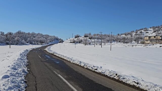 Snow-covered winter landscape with a curving road, distant mountains, and clear blue sky, capturing the calm beauty and quiet atmosphere of a bright cold-season day.  
📍Marivan, Kurdistan 