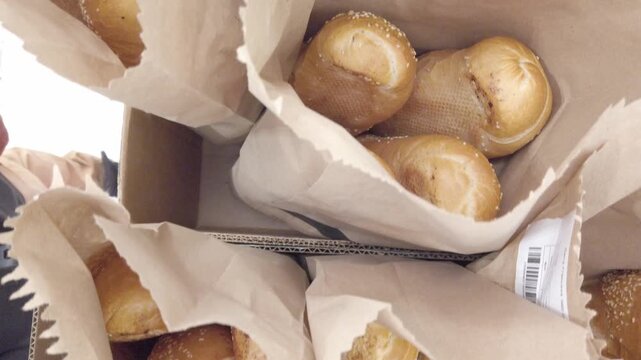 Freshly baked bread loaves packed in paper bags, close up food detail with natural light.