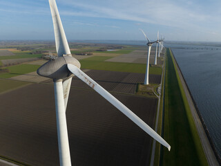 Wind turbines generating clean electricity along a dike landscape