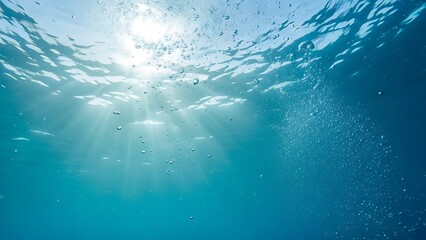 Obraz premium Underwater scene with sunbeams shining through ocean surface and air bubbles rising